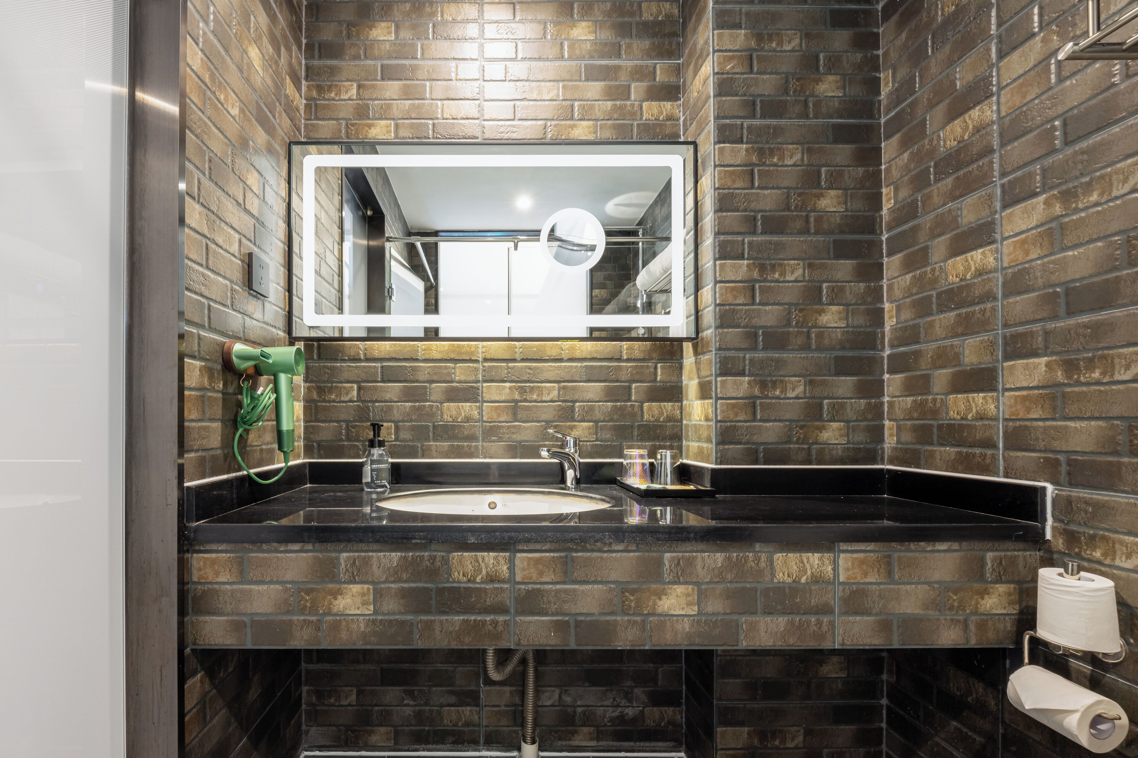 A bathroom with a black sink, a mirror, and a towel dispenser.