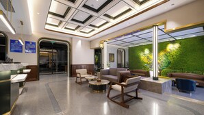 A modern lobby with a reception desk, seating area, and a green wall with a textured pattern. - Nostalgia Hotel（Beijing Jinsong） (Beijing)