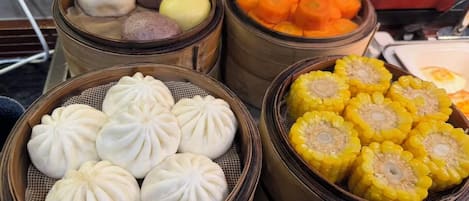 Diversos bollos al vapor y pasteles de maíz expuestos en vaporeras de bambú.