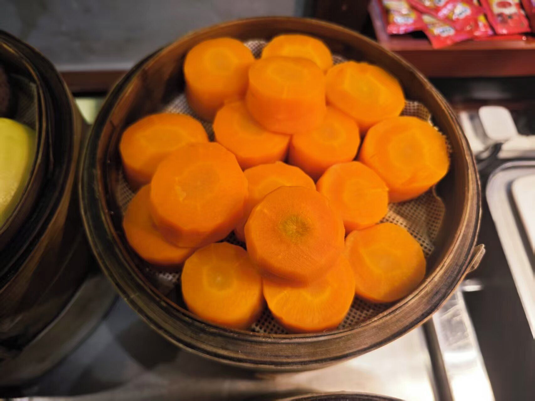 A colander filled with sliced carrots on a kitchen counter.