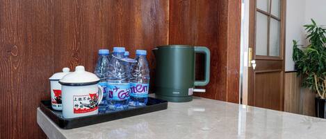 A tray with water bottles, a mug, and two containers on a marble countertop.