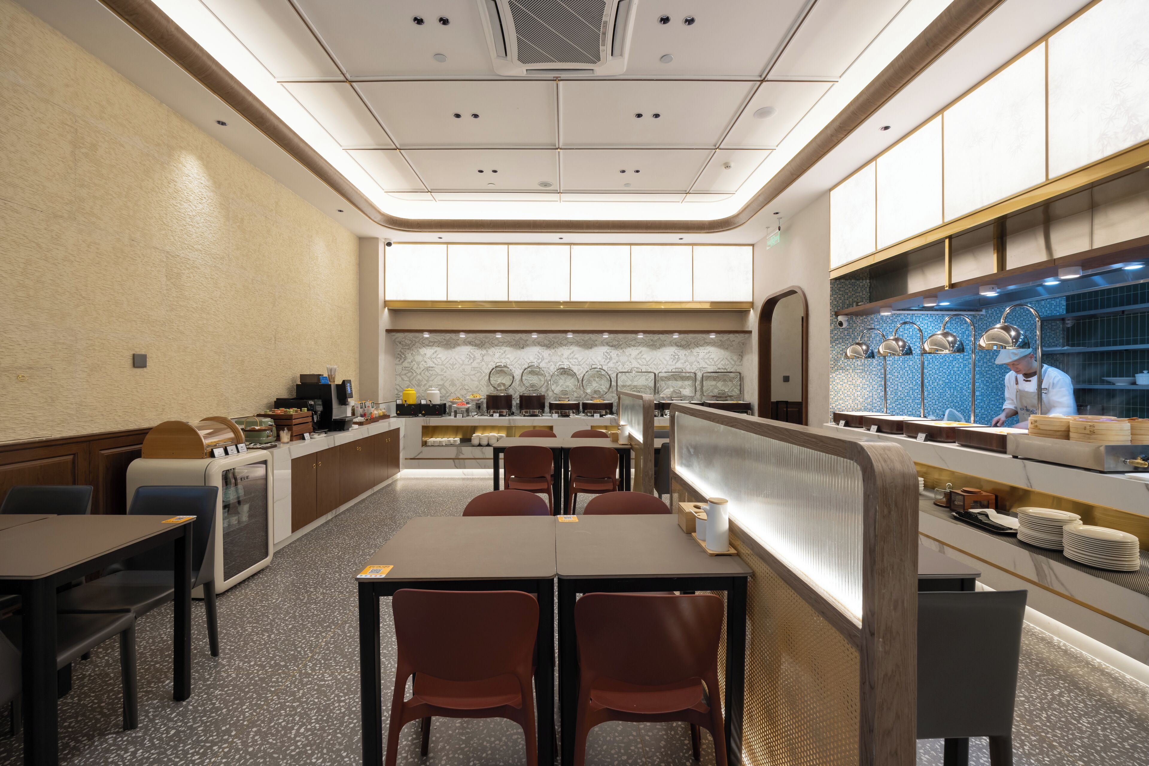 Un ristorante moderno con un lungo bancone, cabine e uno chef alla fine.