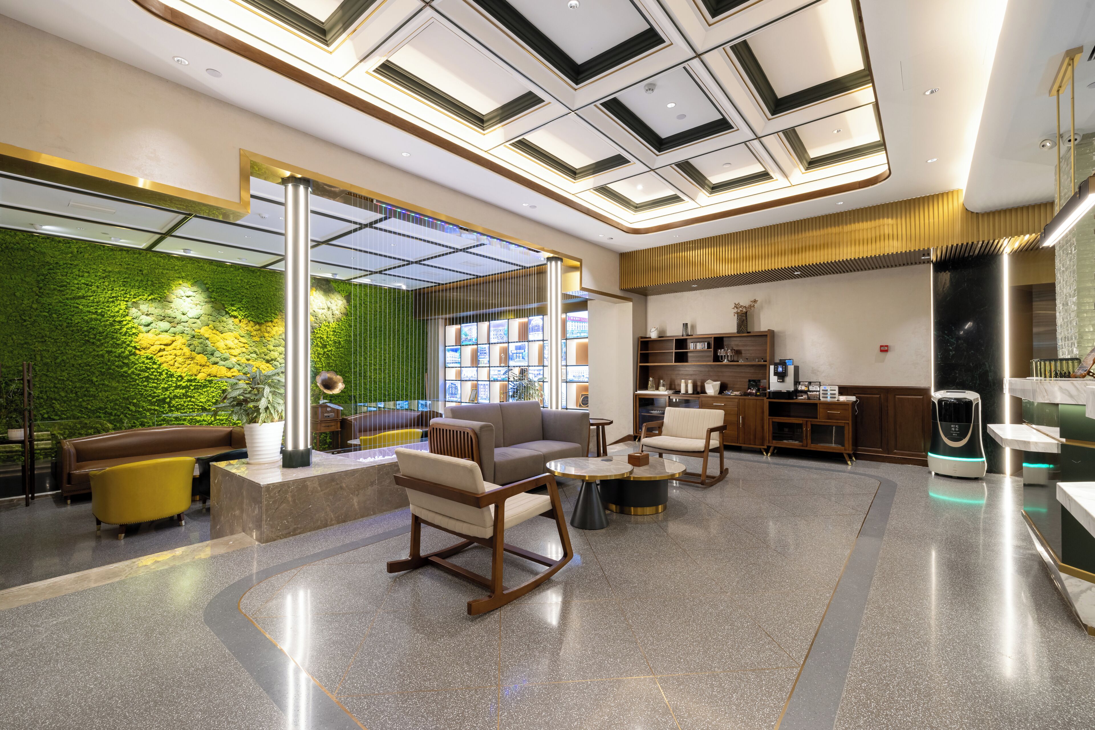 Un lobby moderno con una pared verde, zona de estar y una cocina al fondo.