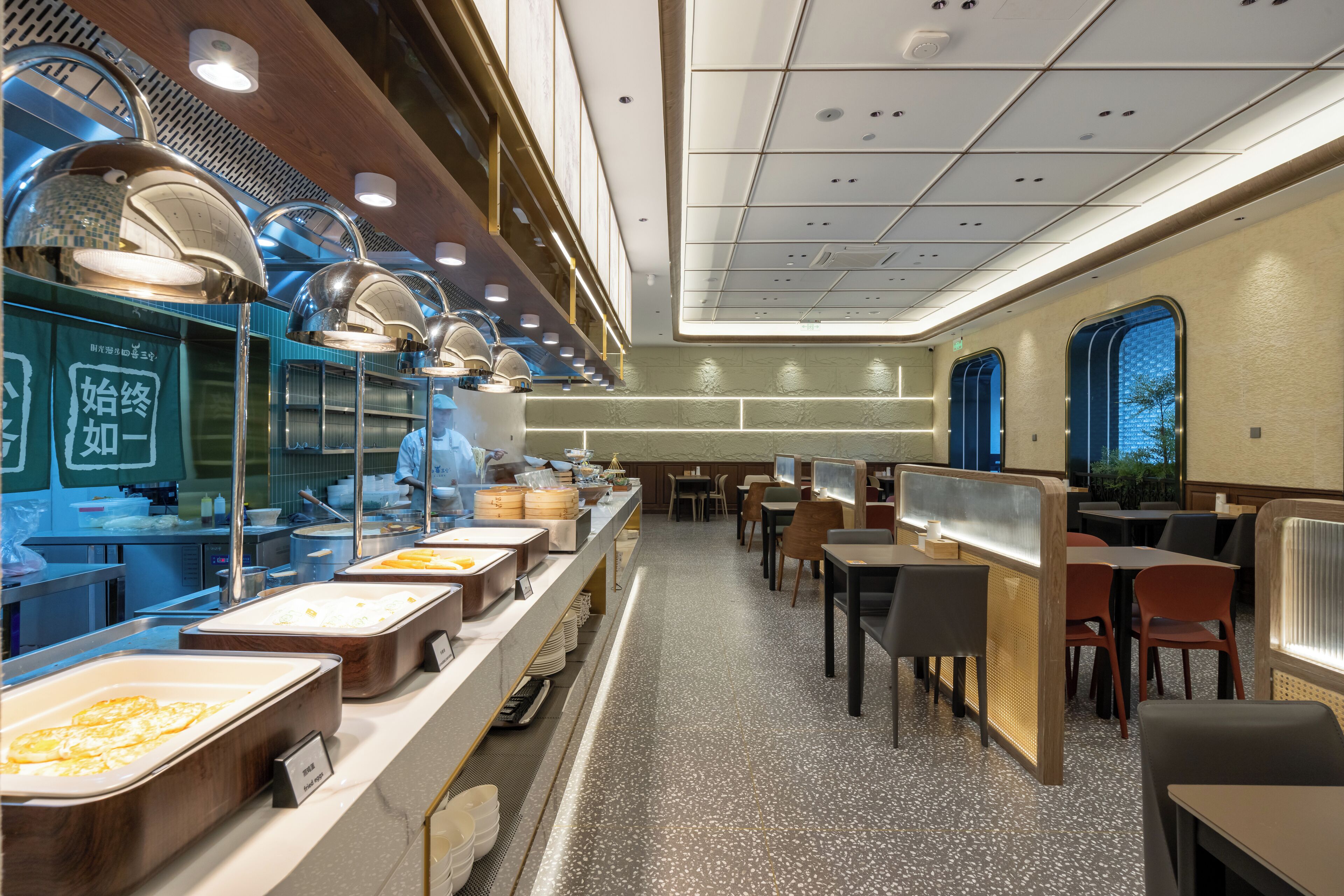 Un espace buffet comprenant plusieurs points de service, des tables et des chaises disposées pour permettre aux convives de se restaurer.