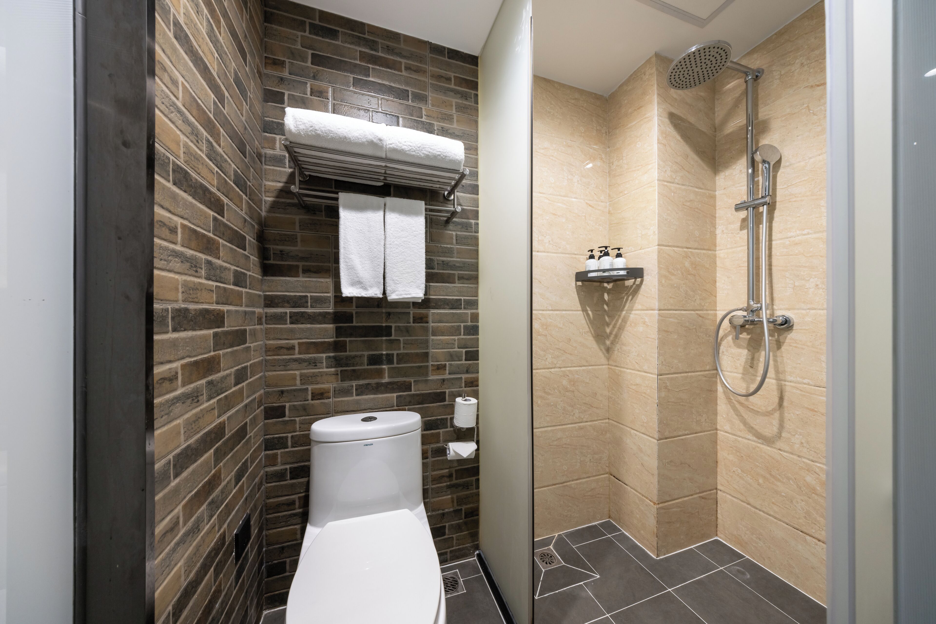 A compact bathroom with a toilet, a towel rack, and a shower.