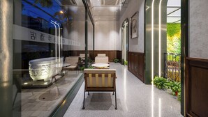 A modern interior with a seating area, a decorative bathtub, and a view of greenery outside. - Nostalgia Hotel（Beijing Jinsong） (Beijing)