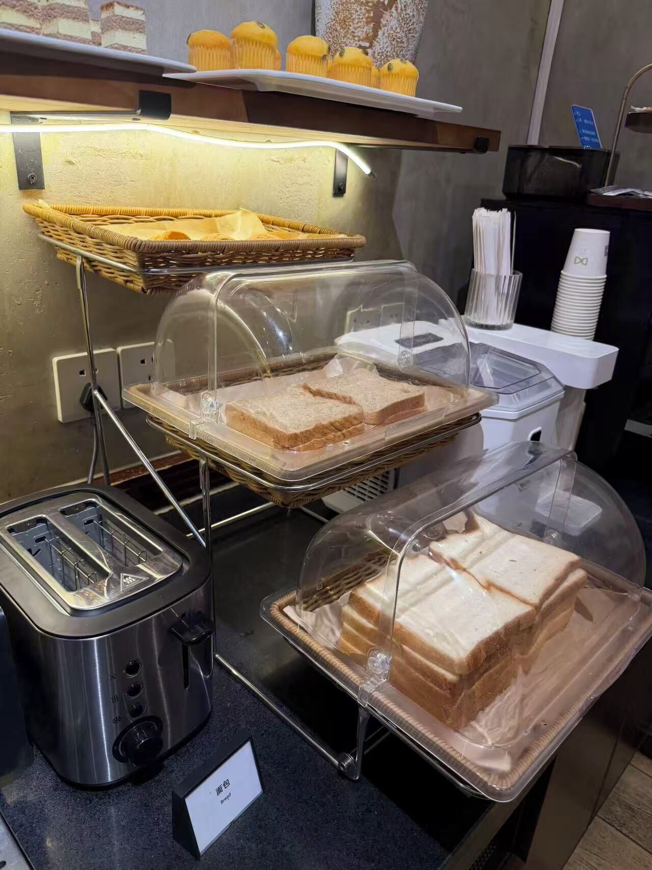 A buffet setup with bread, sandwiches, and muffins.