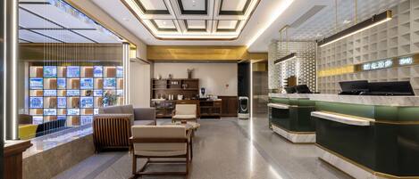Un vestíbulo de hotel moderno con una recepción, un área de descanso y una exhibición de pantallas.