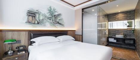 Une chambre d’hôtel moderne avec un grand lit, une table de chevet avec une lampe, un téléphone et un tableau au mur.