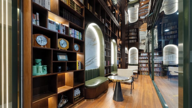 A library interior with wooden bookshelves, seating areas, and clocks. - Nostalgia Hotel（Beijing Jinsong） (Beijing)
