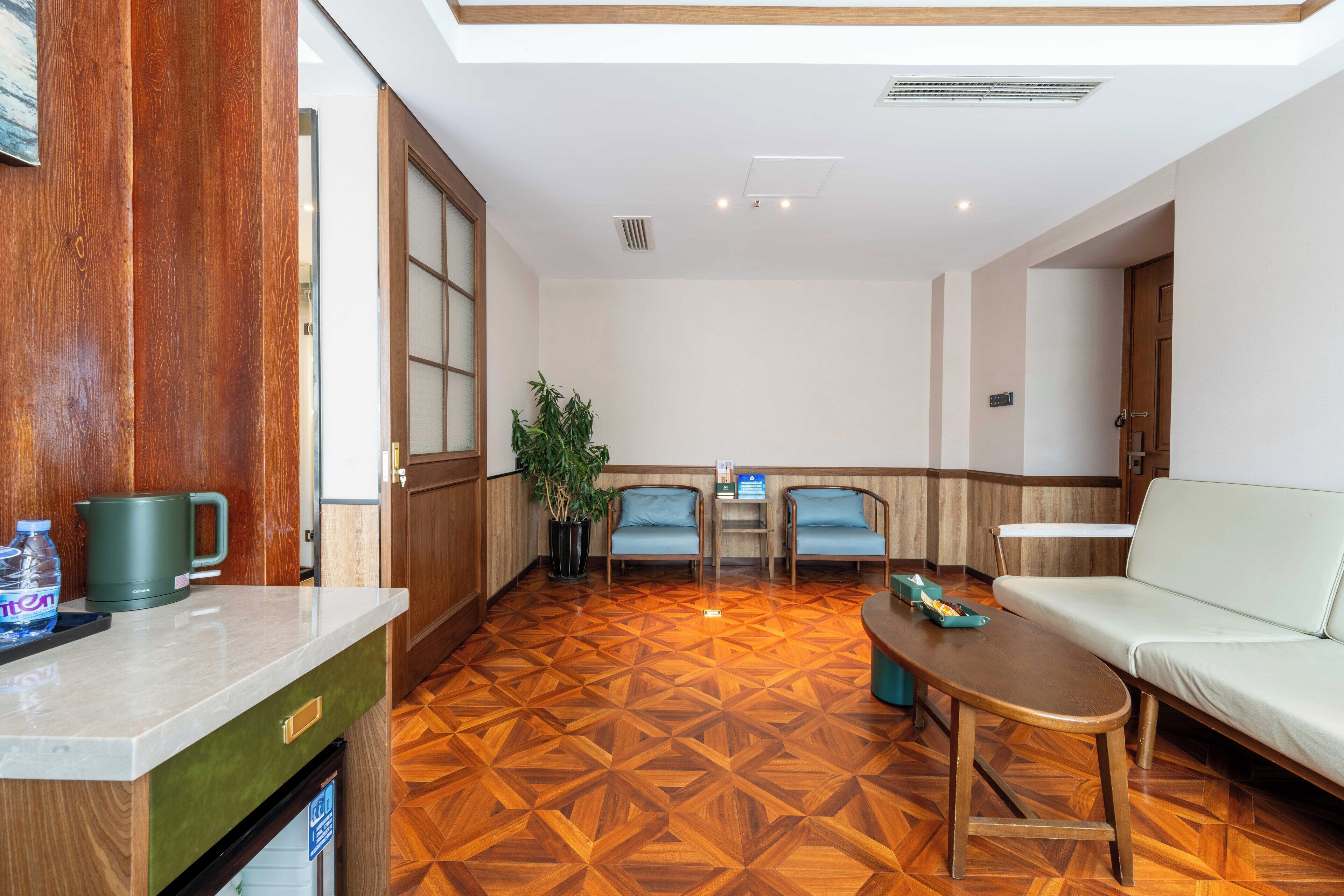 A hotel lobby with a wooden floor, seating area, and a reception desk.