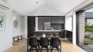 Une cuisine moderne avec un îlot central, des chaises noires et une table à manger.