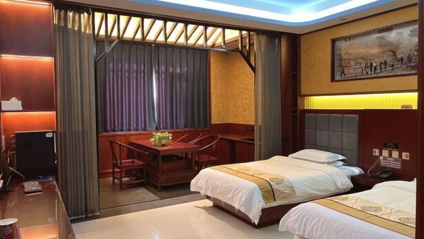 A hotel room with two beds, a desk with a computer, a dining table with chairs, and a large painting on the wall. - HongxingyangExpressHotel (Wuxiang)