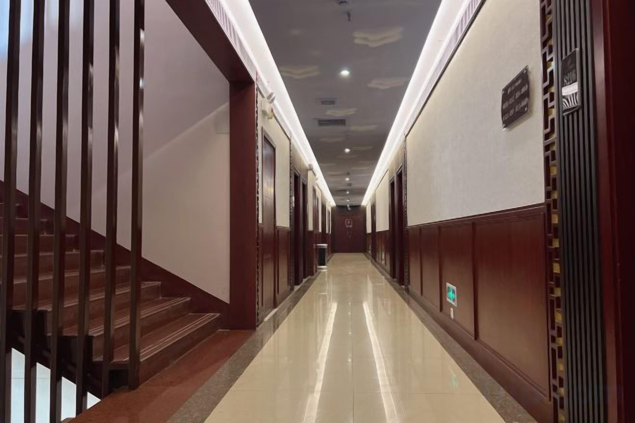 A long, narrow hallway with a staircase on the left and a door on the right.