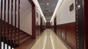 A hotel corridor with a polished floor, wooden doors, and a staircase on the left. - HongxingyangExpressHotel (Wuxiang)