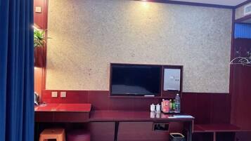 A room with a red desk, a television, and a small stool.