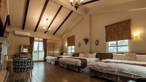 A hotel room with a high ceiling, wooden beams, a fireplace, a desk, and three beds. - Cloud Florence Homestay (Hualien)