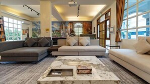 A modern living room with a sectional sofa, a coffee table, and a mural on the wall. - Cloud Florence Homestay (Hualien)