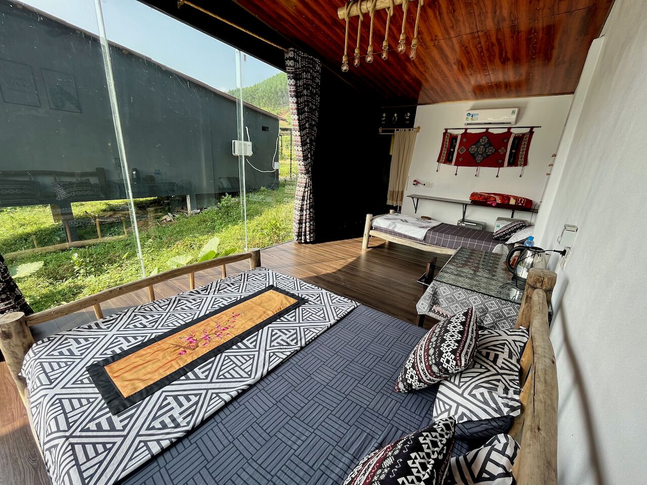 A bedroom with a large bed, a wooden headboard, and a view of the outdoors.