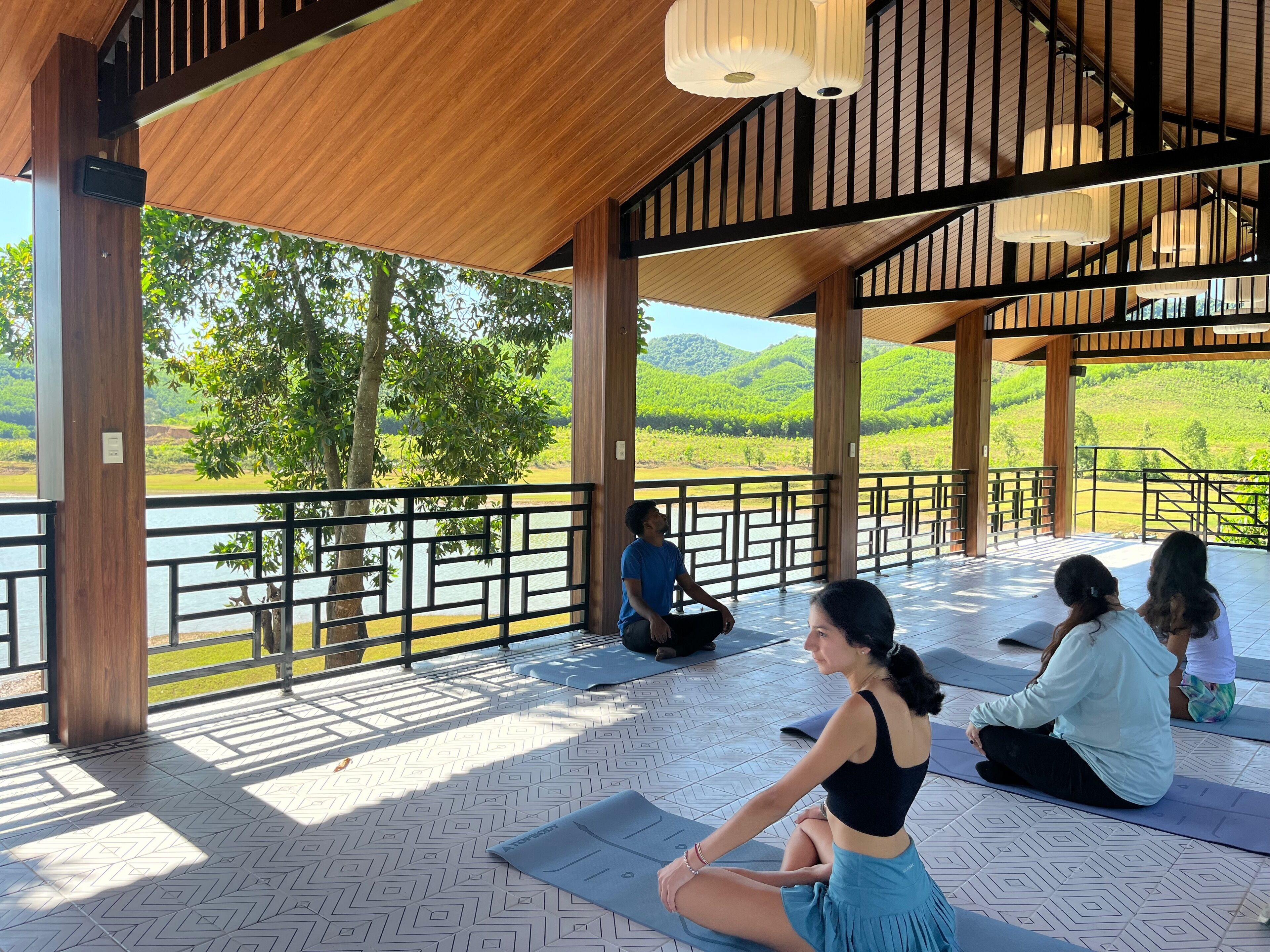 A covered outdoor area with wooden beams and a view of a lake and hills.
