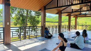 A covered outdoor area with wooden beams and a view of a lake and hills.