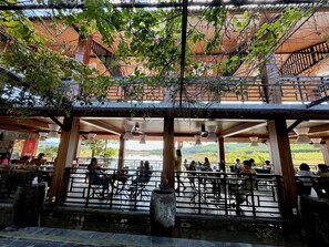 Un restaurante al aire libre con vistas a un lago y colinas.
