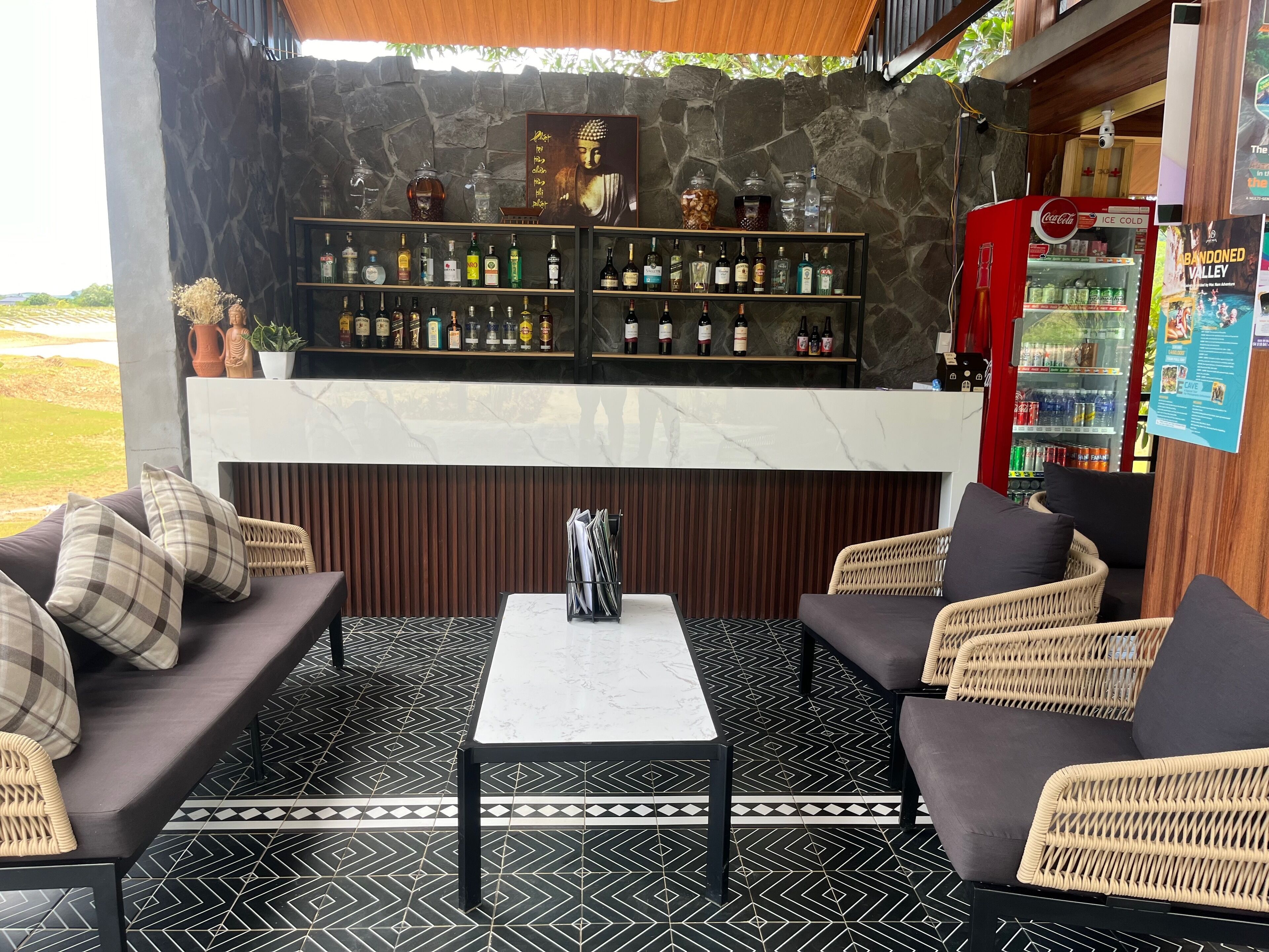 A bar area with a stone wall, shelves of liquor bottles, and a Coca-Cola cooler.