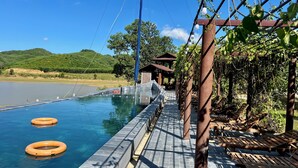Un espace piscine avec une eau claire, des bouées et une pergola couverte de plantes grimpantes.