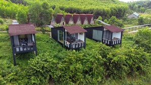 Trois petits chalets dotés de balcons, entourés d’une végétation luxuriante.