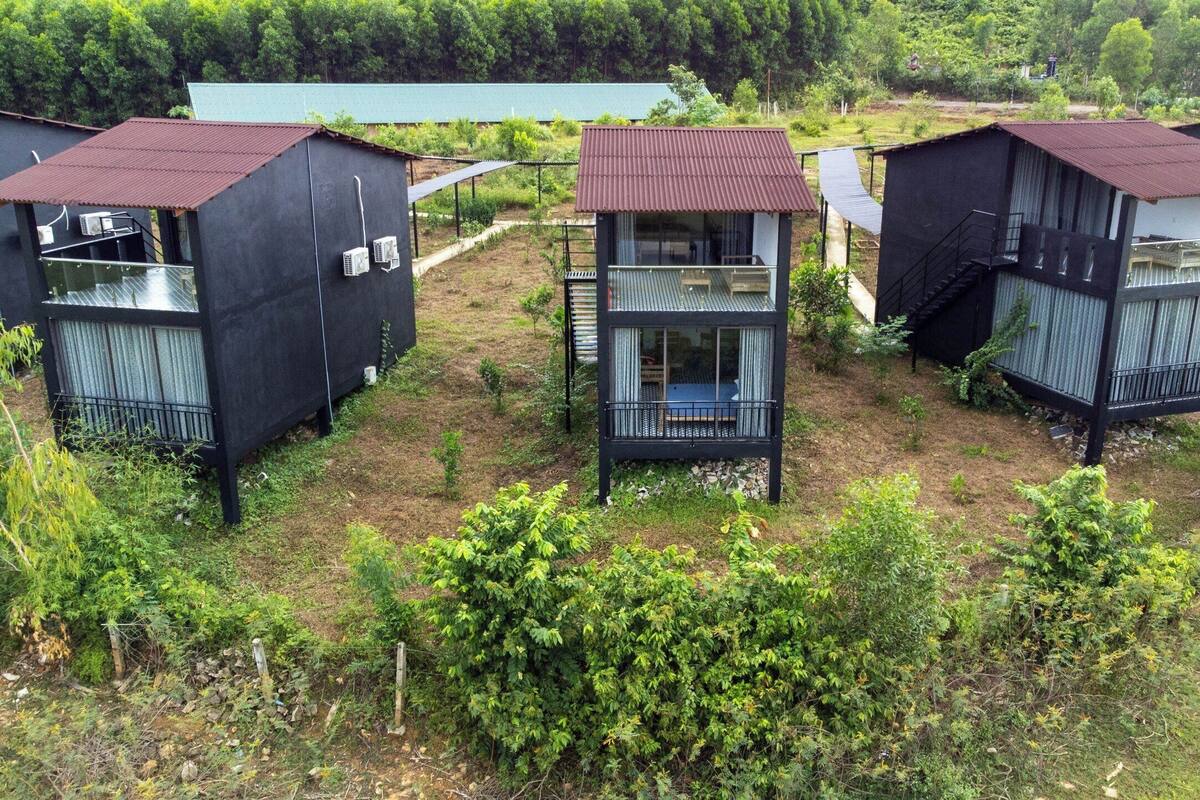 A cluster of black cabins with metal roofs, surrounded by greenery.