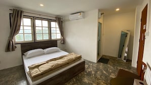 A bedroom with a bed, a window with curtains, an air conditioning unit, and a small table with a tissue box. - cumpun hostel (Chiang Mai)