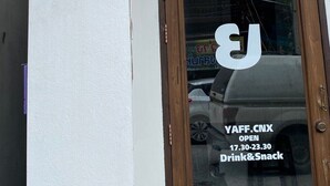 A building with a sign that reads "cumpun hostia" and a door with a sign stating "YAFF.CNX OPEN 17.30-23.30 Drink&Snack". - cumpun hostel (Chiang Mai)