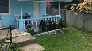Una casa azul con porche, un pequeño jardín y un muro de concreto.