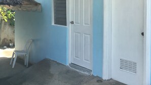 Una casa con fachada azul, puerta blanca y porche de hormigón.