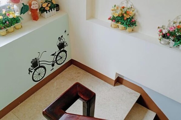 A staircase with a wooden handrail and a light green wall with a black bicycle decal.