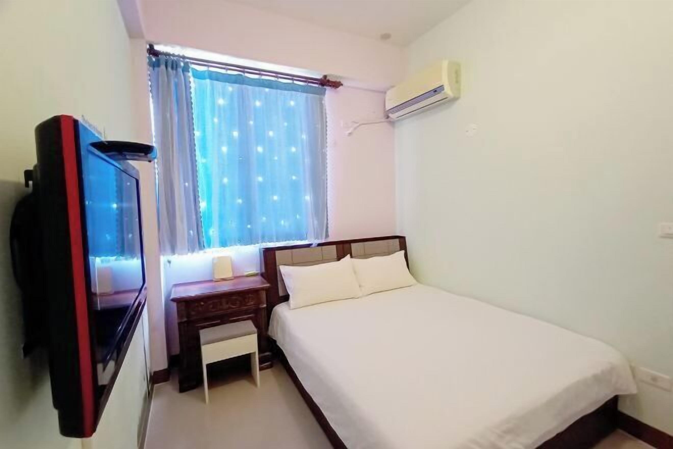 Una habitación de hotel con una cama, un escritorio, un televisor y un aire acondicionado.