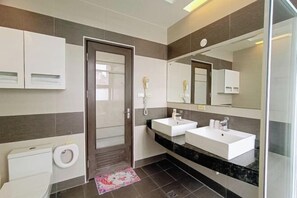 A modern bathroom with two sinks, a toilet, and a shower.