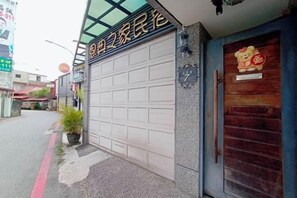 A building with a garage door, a wooden door with a bear decoration, and a small potted plant.