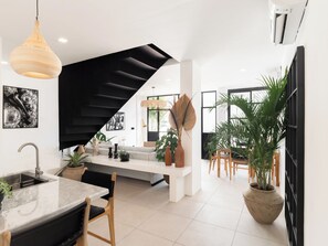 Experience the perfect blend of functionality and style in this modern space, featuring a sleek kitchen, black staircase, and beautiful artwork.