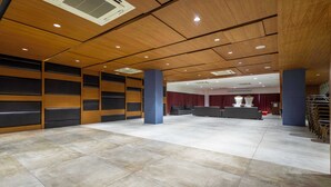 A spacious lobby with a high ceiling, recessed lighting, and a stage area with curtains. - Treebo Blue Moon (Gandhinagar)