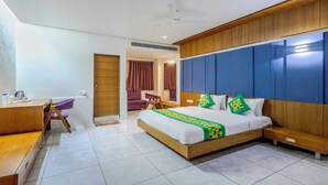 A modern hotel room with a wooden bed, a desk, and a purple armchair. - Treebo Blue Moon (Gandhinagar)