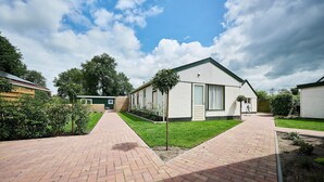 Uma área residencial com uma calçada pavimentada que leva a uma casa moderna com telhado inclinado e grandes janelas.