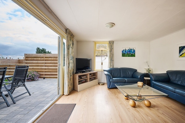 A living room with a TV, sofas, a coffee table, and a view of the outdoors.