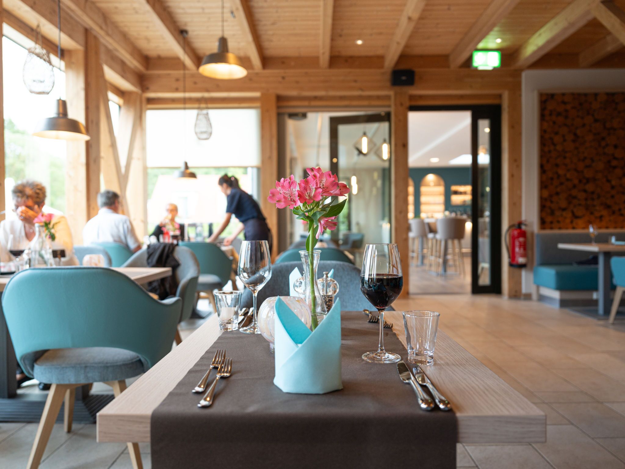 Ein Restaurant mit gedeckten Tischen, einem Blumenstrauß und einem sichtbaren Feuerlöscher.