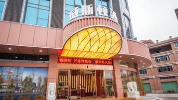 A hotel entrance with a large illuminated sign, a curved facade, and a statue in front.