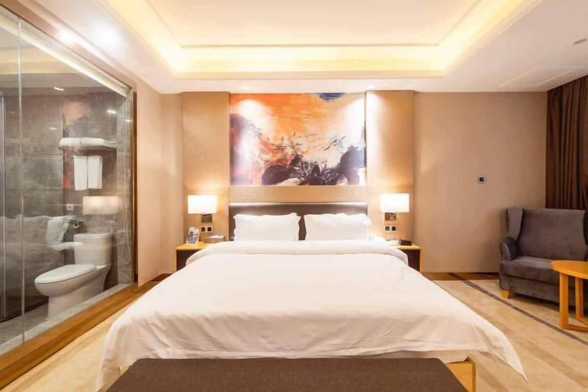 Ein Hotelzimmer mit Bett, Duschkabine aus Glas, einem Bild an der Wand und einer Sitzecke.
