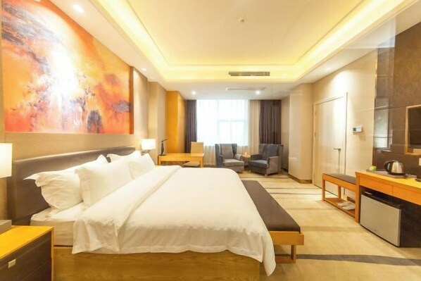 A hotel room with a bed, a desk, a chair, a TV, and a large abstract painting on the wall.