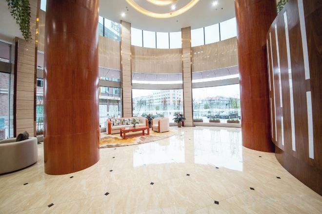 Un hall amplio con zona de estar central, pilares grandes y vistas al exterior.