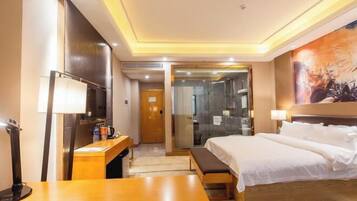 A hotel room with a bed, bedside table, lamp, and a painting on the wall.