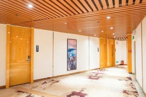 A hotel corridor with wooden doors, a framed picture on the wall, and a patterned carpet. - Weisidun Hotel (Dongguan)